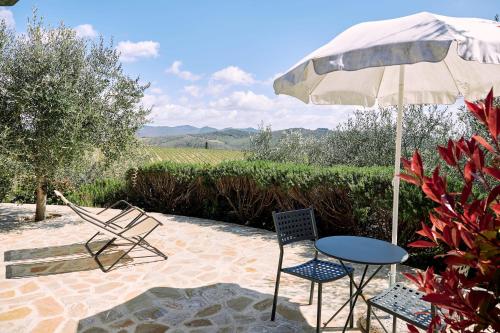 a patio with a table and chairs and an umbrella at Agriturismo San Sano in Gaiole in Chianti