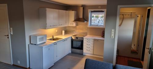 a kitchen with white cabinets and a sink and a window at Sokkelleilighet på Kolnes in Tananger