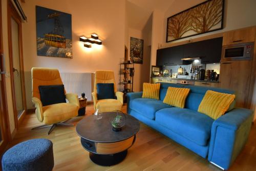 un salon avec un canapé bleu et des chaises dans l'établissement VAUJANYLOCATIONS - EdelweissD07, à Vaujany