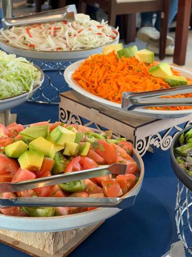 a table topped with plates of vegetables and carrots at Tequendama Hotel Medellín - Estadio in Medellín