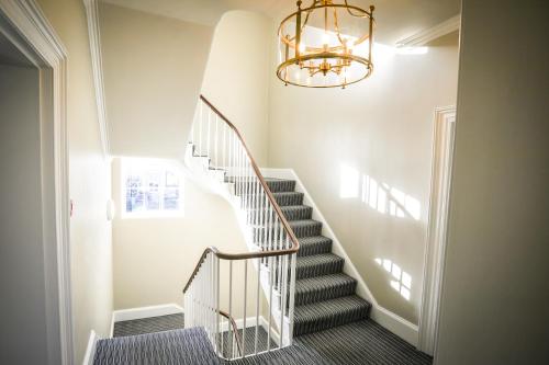 a staircase with a chandelier in a house at The Lazy Goose - Coffee House & Bedrooms in Stonehouse