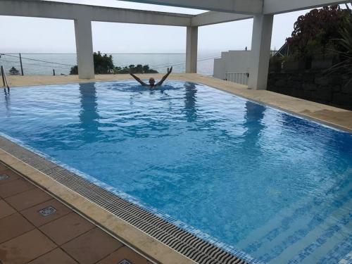 a person is laying in a swimming pool at Sky Apartamentos Vista Do Atlântico in Capelo