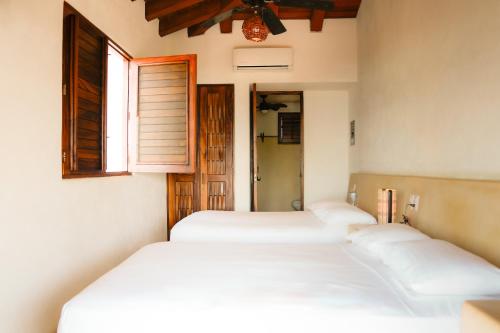 a row of four beds in a room with a window at Refugio de piedra - Troncones in Troncones