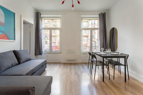 un salon avec un canapé et une table avec des chaises dans l'établissement Appartement idéal pour visiter Strasbourg, à Strasbourg