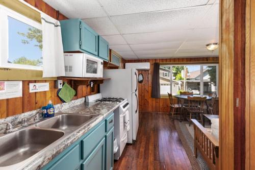 a kitchen with blue cabinets and white appliances at Chippewa Bluffs Resort Combined 3BR 3BA Cabins in Barryton