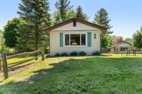 a house with a fence and a yard at Chippewa Bluffs Resort Combined 3BR 3BA Cabins in Barryton