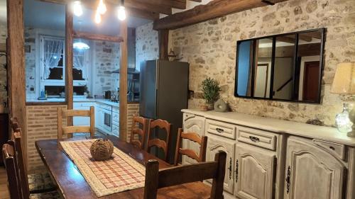 a kitchen with a table and a television on the wall at La Manounière in Mauchamps