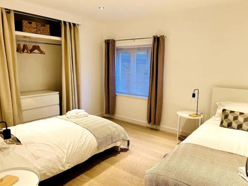 a bedroom with two beds and a window at 1 Old Sefter School House in Bognor Regis