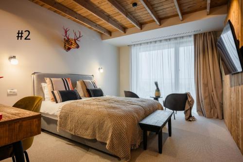 a bedroom with a large bed and a large window at The Pines Bucegi Lodge in Bran