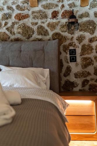 a bed in a room with a stone wall at Πηγή Τραγανιστή in Kato Trikala Korinthias
