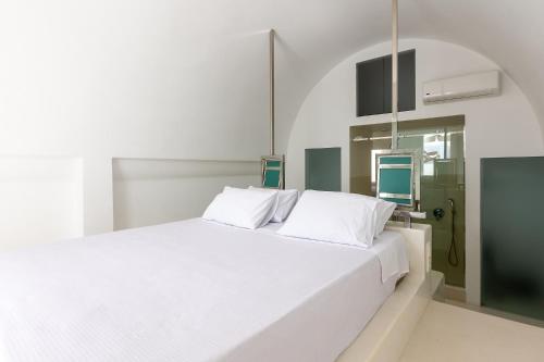 1 cama blanca con almohadas blancas en una habitación en Santorini Sun Villas, en Oia
