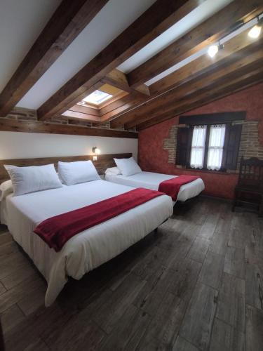 two beds in a room with wooden ceilings at Apartamentos Legado de Santillana in Santillana del Mar