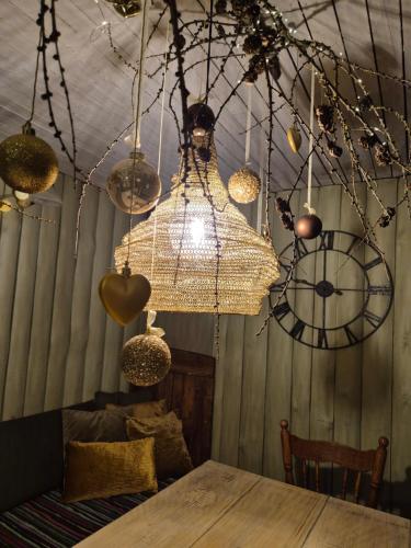 a chandelier hanging from a ceiling with a clock at Mošķu Pirts meža māja in Turaida