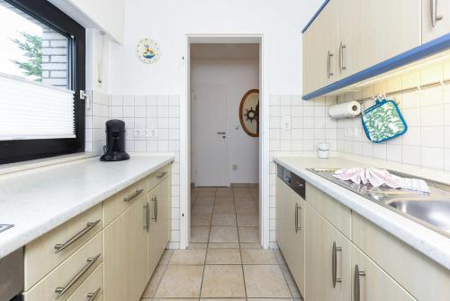 a kitchen with white cabinets and a sink and a window at Ferienhaus Boje 13 in Neuharlingersiel