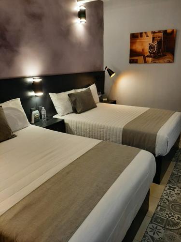 a hotel room with two beds and a camera on the wall at Añoranza Hotel Boutique in Ciudad Hidalgo
