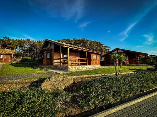 a log cabin with a yard and a house at Ericeira Camping in Ericeira