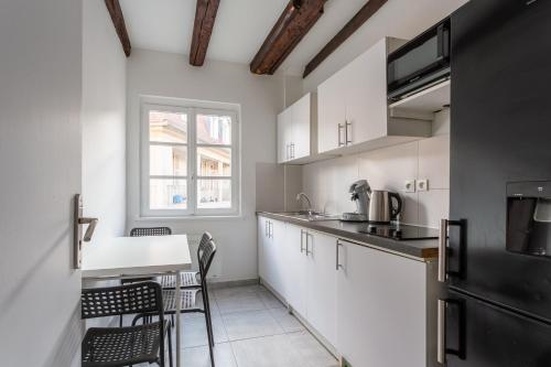 une cuisine avec des armoires blanches et une table et des chaises dans l'établissement Confort au cœur de Strasbourg, à Strasbourg