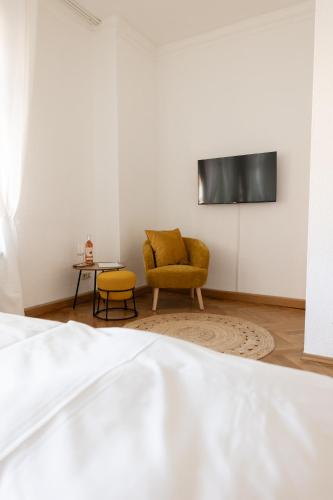a room with a chair and a tv on a wall at Gästehaus am Winckel in Stendal