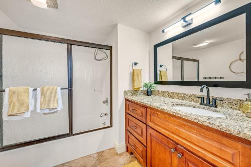a bathroom with a shower and a sink and a mirror at Sandpiper Beacon Beach Resort in Panama City Beach