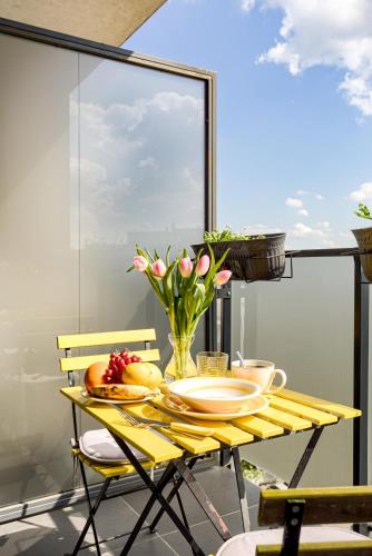 a yellow table with a vase of flowers on it at ARI - ARED Luxurious Apartments with Balcony & Free Parking in Arad