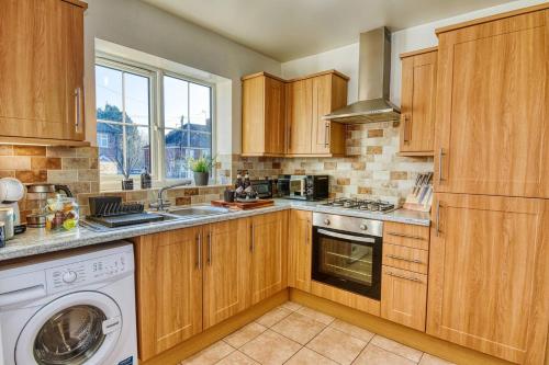 a kitchen with wooden cabinets and a washer and dryer at Gornal Dudley-2bed-Contractor &Long stay -Parking in Gornalwood