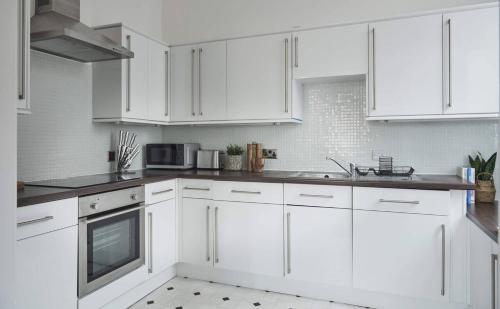 a white kitchen with white cabinets and a sink at Dudley-Spacious Exec 2 bed - Long stay - Parking! in Dudley
