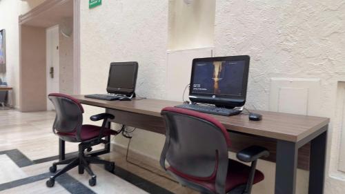 two computers sitting on a wooden desk with chairs at Best Western PLUS Monterrey Colón in Monterrey