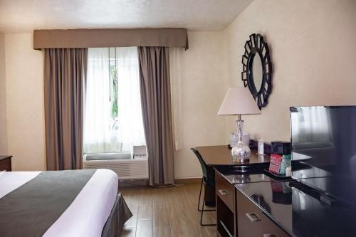 a hotel room with a bed and a desk and a window at Best Western PLUS Monterrey Colón in Monterrey