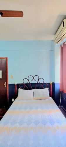 a bedroom with a bed with a blue wall at Príncipe Hotel Maringá in Maringá