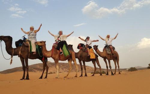 a group of people riding on camels in the desert at Camp trip Merzouga in Merzouga