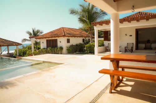 a house with a swimming pool and a bench at Refugio de piedra - Troncones in Troncones