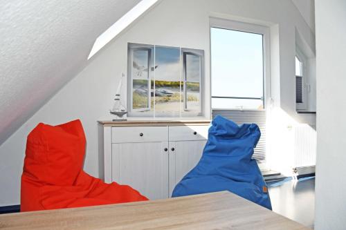 2 rote und blaue Stühle in einem Zimmer mit Fenster in der Unterkunft schöne Ferienwohnungen in Dranske auf dem Windland in Dranske
