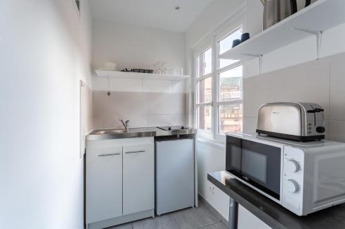 une cuisine blanche avec un évier et un micro-ondes dans l'établissement Appartement au centre de Strasbourg, à Strasbourg