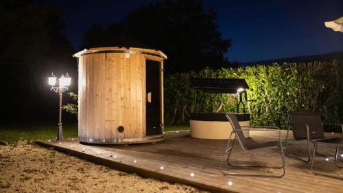 une cabine en bois avec des chaises, une table et des lumières dans l'établissement La Lovrette - Maisonnette Romantique avec Balnéo, Sauna Privatif et Expériences Érotiques, à Saint-AndrÃ©-sur-Orne