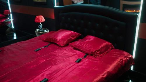 - un lit rouge avec une couette et des oreillers rouges dans l'établissement La Lovrette - Maisonnette Romantique avec Balnéo, Sauna Privatif et Expériences Érotiques, à Saint-AndrÃ©-sur-Orne