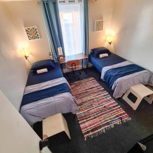 a room with two beds and a rug at ITH Hermosa Beach Surf Hostel LAX in Hermosa Beach
