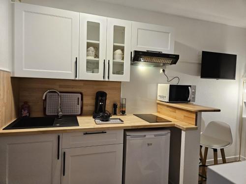 une cuisine avec des armoires blanches, un évier et un micro-ondes dans l'établissement T2 neuf - centre - Parking supp, à Toulouse