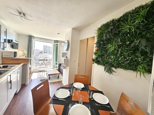 une cuisine avec une table avec des chaises et une plante au mur dans l'établissement T2 neuf - centre - Parking supp, à Toulouse