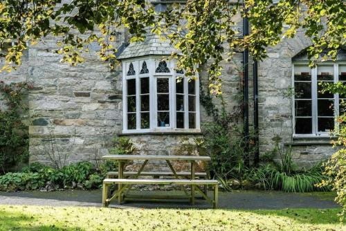 un banc en bois assis devant un bâtiment dans l'établissement Large Grade II Listed House & Garden nr Beaches, à Saint Columb Major