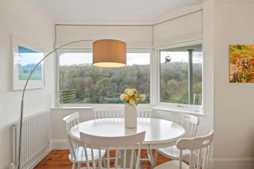 a white dining room with a white table and chairs at Cosy Home on the Waterfront Private Parking in Looe