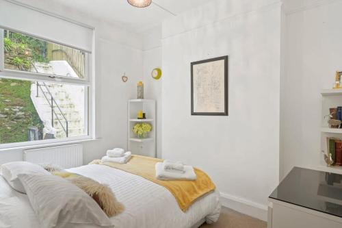 a white bedroom with a bed and a window at Cosy Home on the Waterfront Private Parking in Looe