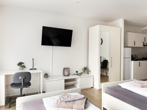 a white bedroom with a bed and a chair and a tv at Apartments in the city center I private parking I home2share in Dortmund