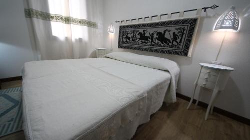 a small bedroom with a white bed and a table at Affittacamere Sa Mariola in Sorgono