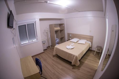 a small room with a bed and a window at Hotel Fontana in Tapejara
