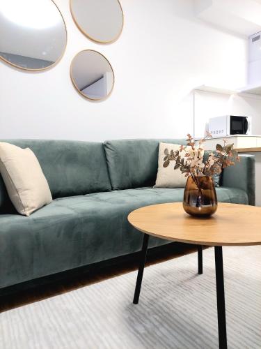 a living room with a green couch and a table at Apartman COMO, private parking free in Košice