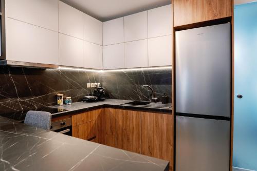 a kitchen with white cabinets and a stainless steel refrigerator at Endless View loft in Mesimvría