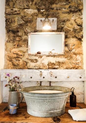 La salle de bains en pierre est pourvue d'un lavabo et d'un miroir. dans l'établissement Maison Secrete Studio Apartment, à Marsalès