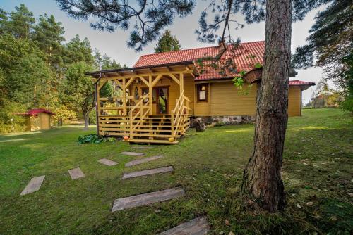a log cabin in a yard with a tree at Siedlisko Sapunki dom z duszą rybaka na Warmii in Bogdany