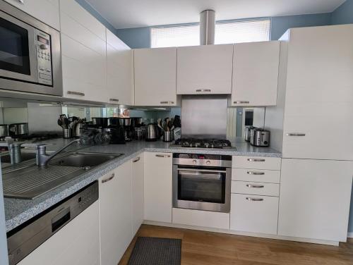 une cuisine avec des armoires blanches et des appareils en acier inoxydable dans l'établissement Ker Maretz Appartement lumineux entre côte et parc, à Pornic