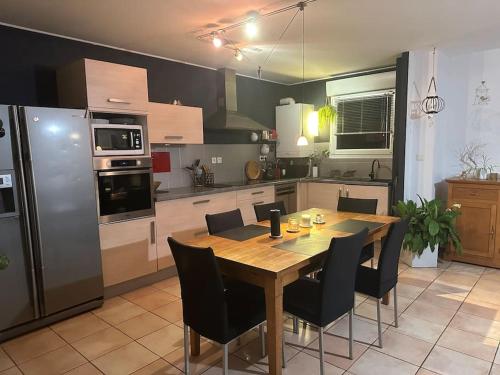 une cuisine avec une table en bois et des chaises noires dans l'établissement Un havre de verdure en ville, à Colmar